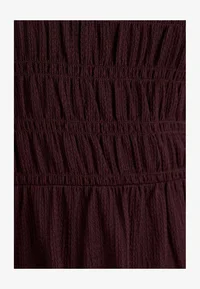 Close-up of the dark red dress fabric and gathered detailing