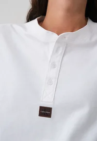 Close-up of white Henley neckline, button placket and Calvin Klein label