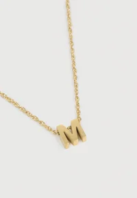 Close-up of the gold-coloured letter M pendant