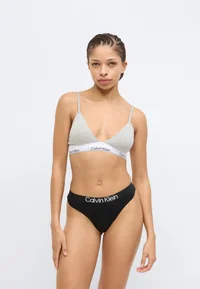 Model wearing black Calvin Klein thong, front view