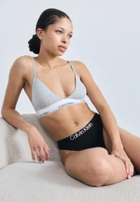 Model wearing black Calvin Klein thong, seated view